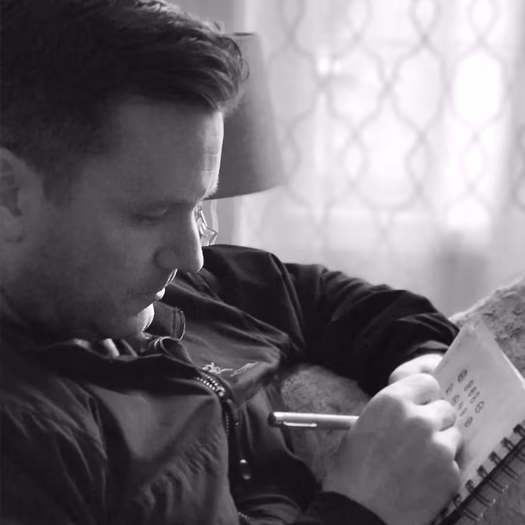 a black and white candid photo of Justin Prno doing quick sketches in a notebook